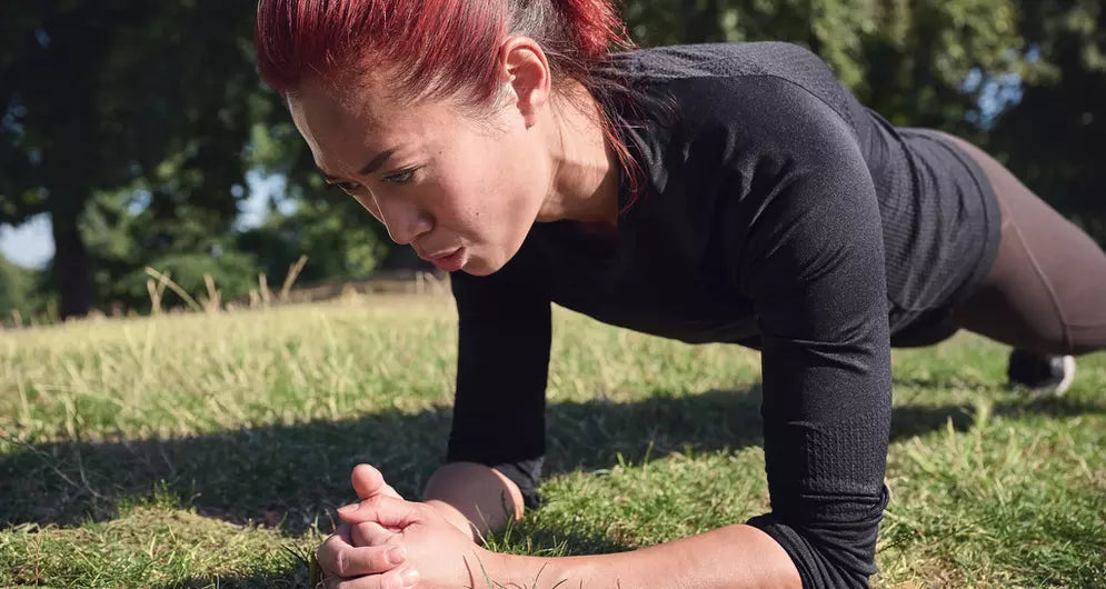 Women with red hair in plank position on grass field