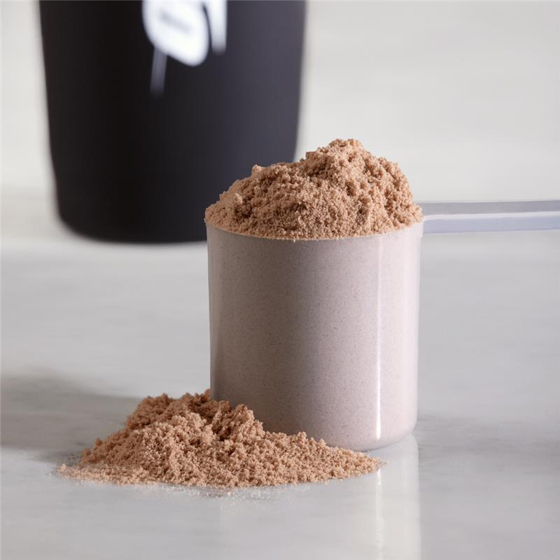 Scoop of protein powder on a table, likely for post-workout nutrition or muscle building