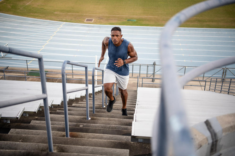 A person running up stadium stairs, potentially engaging in high-intensity workouts for fitness or athletic training