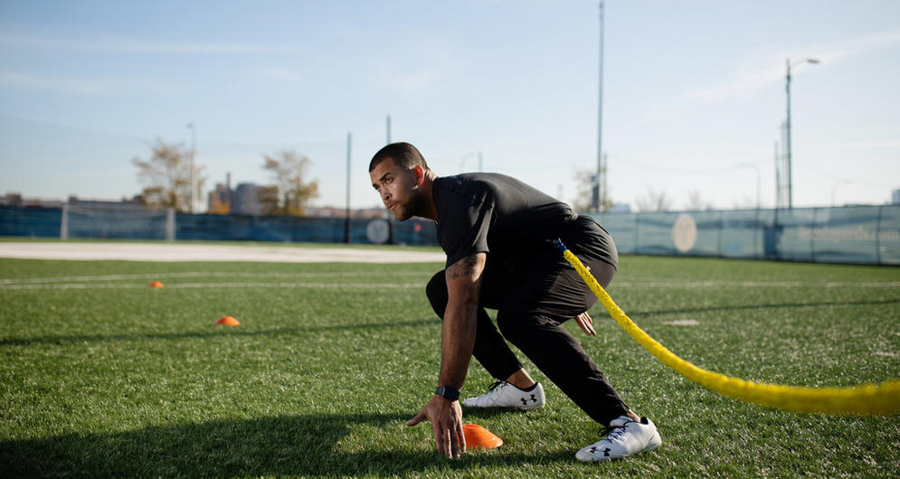 A person engaged in athletic training on a grass field, using a resistance band for high-intensity workouts
