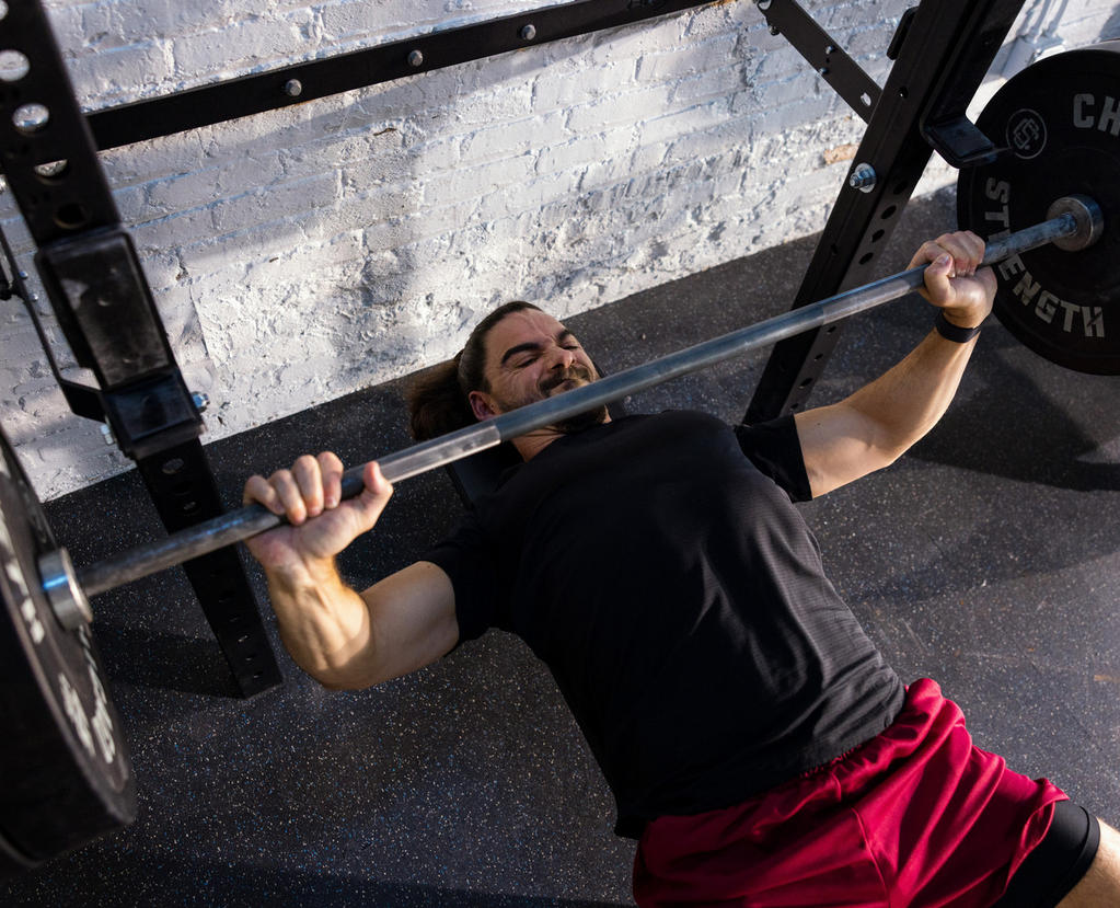 A person performing a bench press exercise with a barbell in a gym setting