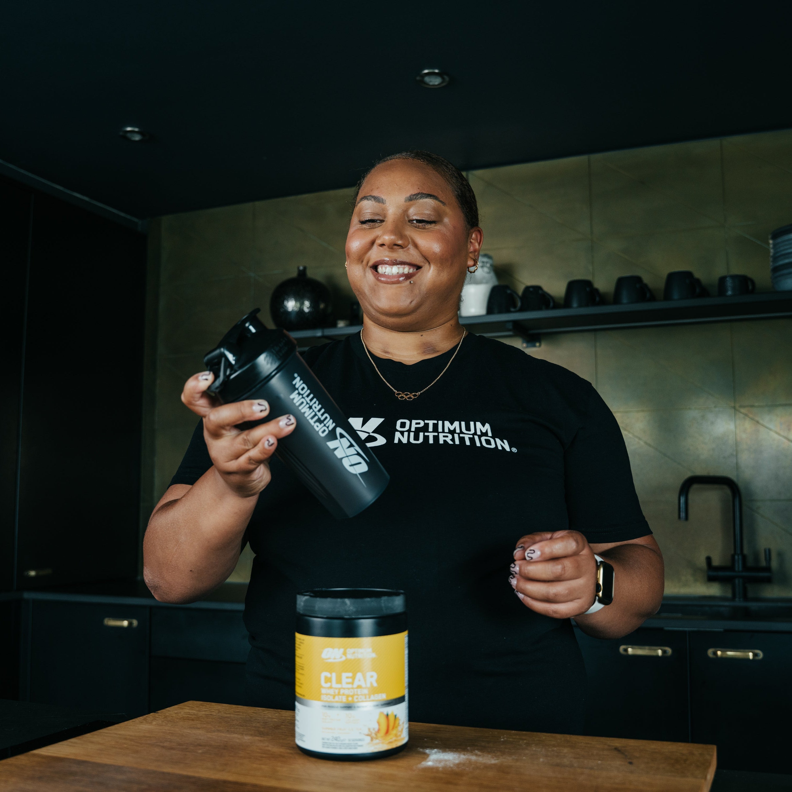 Person holding Optimum Nutrition products in a kitchen