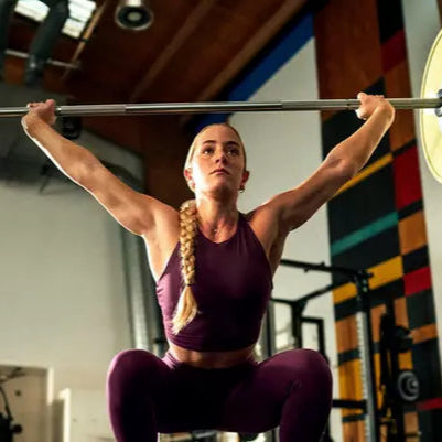 A person lifting a barbell in a gym setting, demonstrating strength training or high-intensity workout