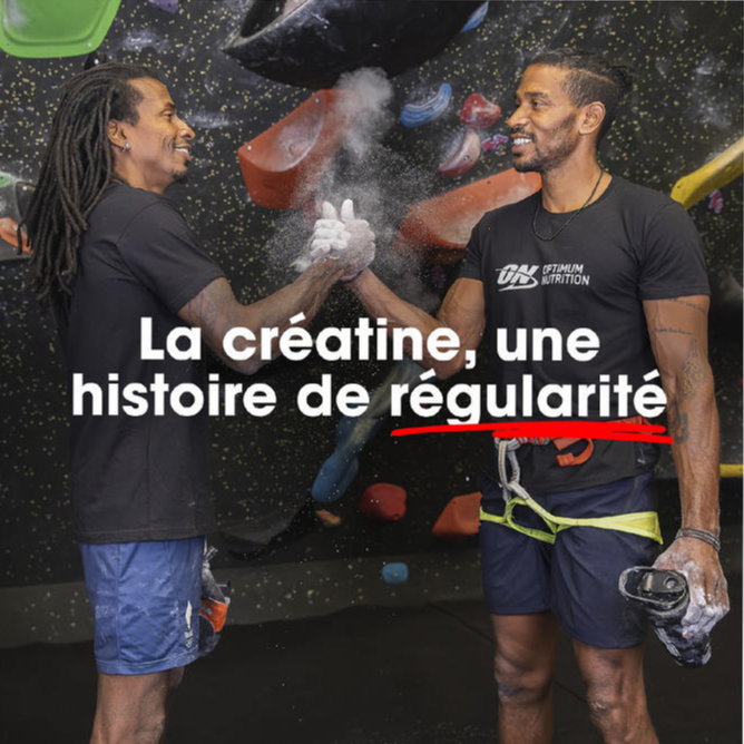 Two people in climbing gear shake hands in a gym. One wears an Optimum Nutrition shirt