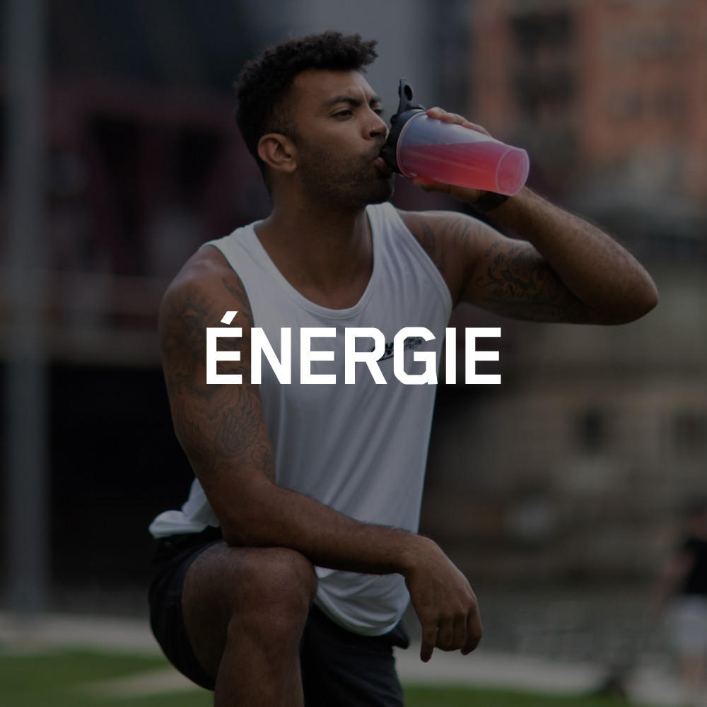 Man drinking from a shaker bottle, possibly containing an amino energy drink, during a workout