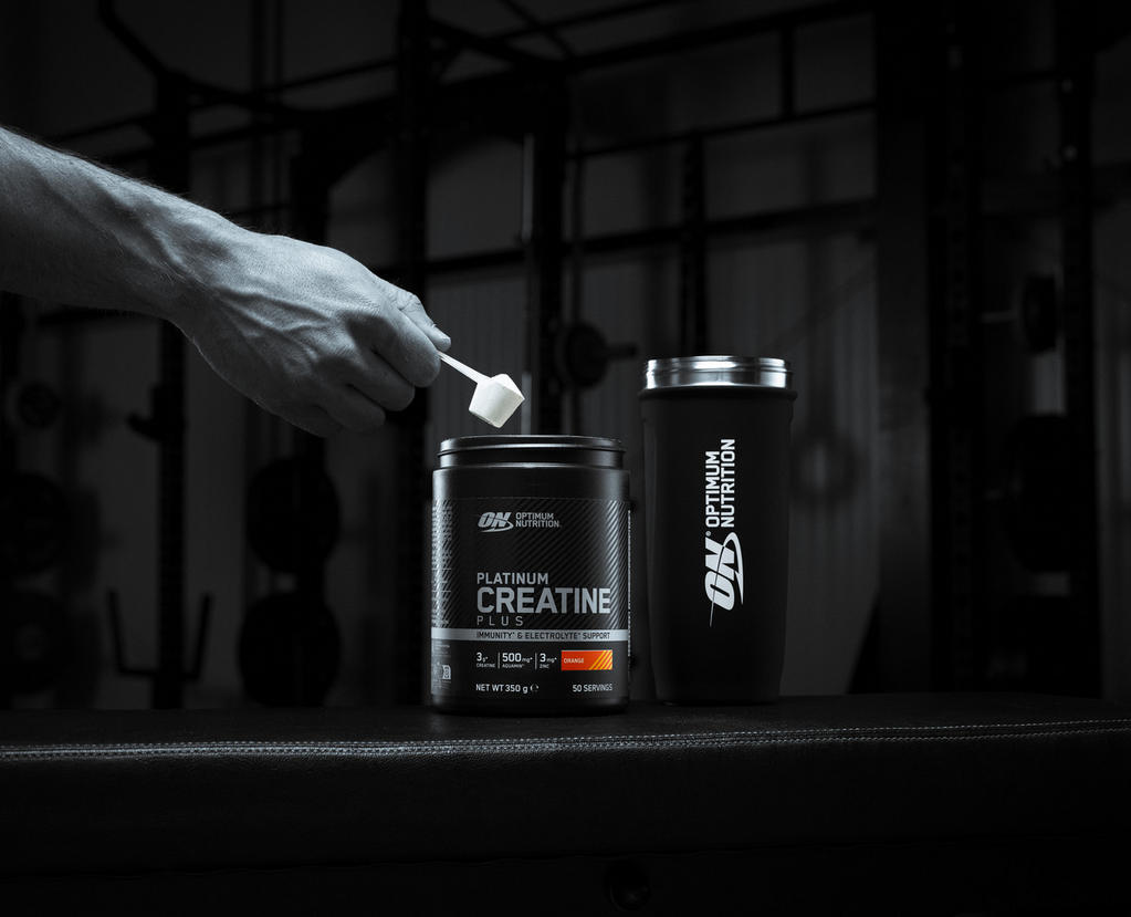 Optimum Nutrition Platinum Creatine Plus container with a scoop, next to an Optimum Nutrition shaker bottle