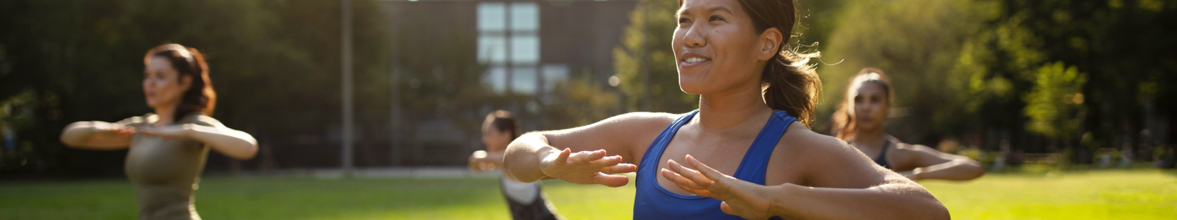 People exercising outdoors in a park, performing fitness routines in a group setting