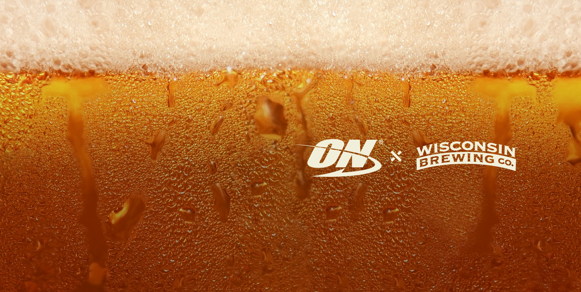 Close-up of a frothy golden beer with condensation droplets and logos for Optimum Nutrition and Wisconsin Brewing Co. near the center.