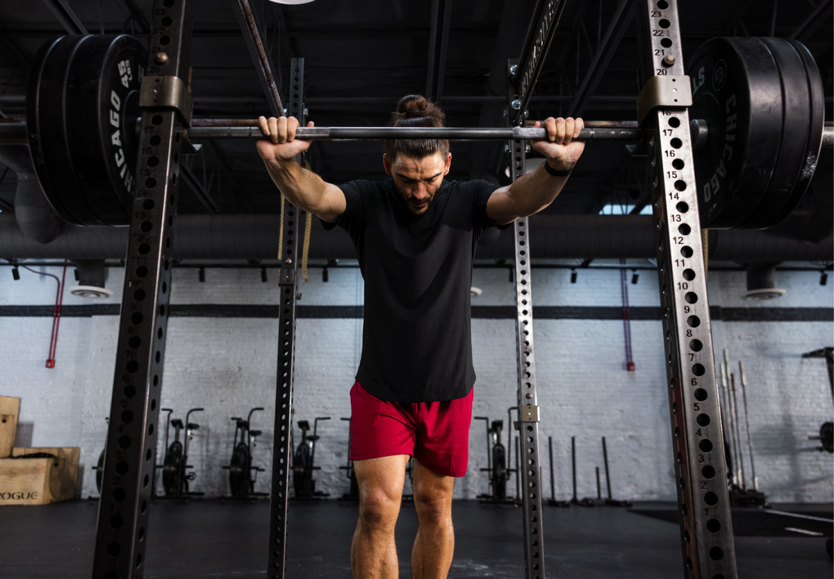 A person lifting a barbell in a gym setting, focusing on strength training