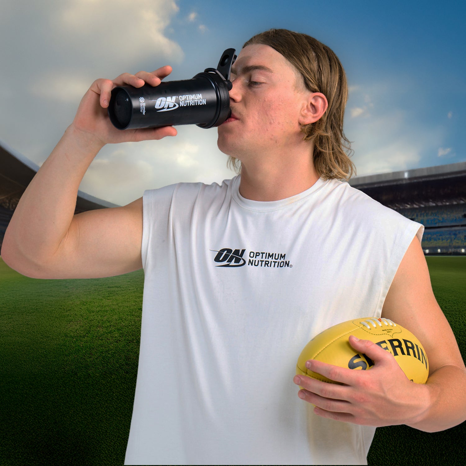 Optimum Nutrition shaker bottle held by a person wearing an Optimum Nutrition shirt, holding a sports ball