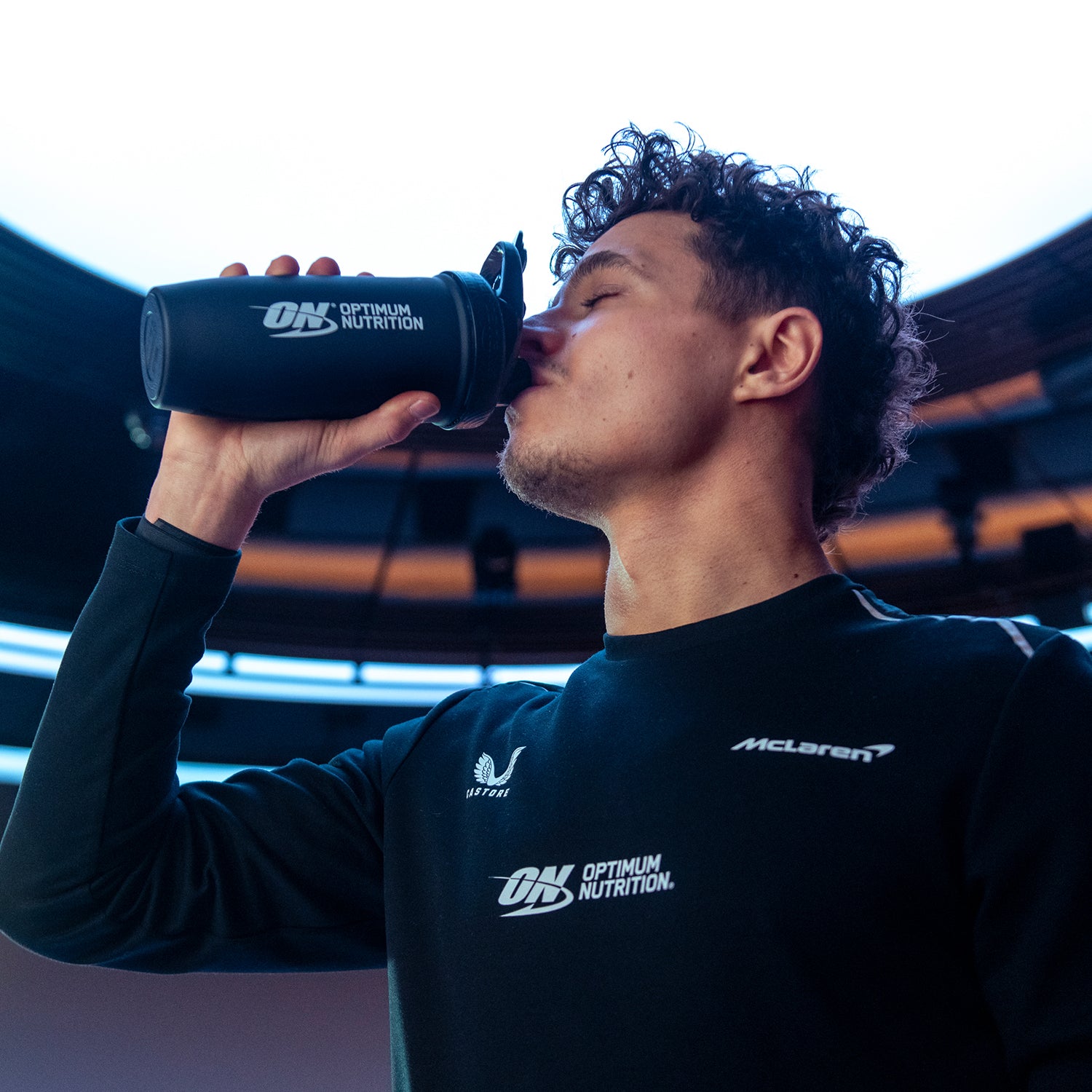 Person drinking from an Optimum Nutrition shaker bottle, associated with fitness and nutrition