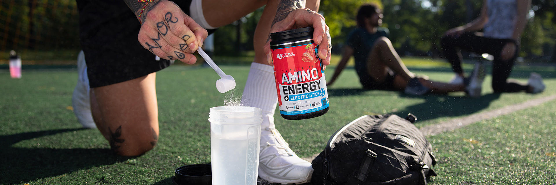 Amino acid energy formula being mixed into a shaker bottle on a sports field