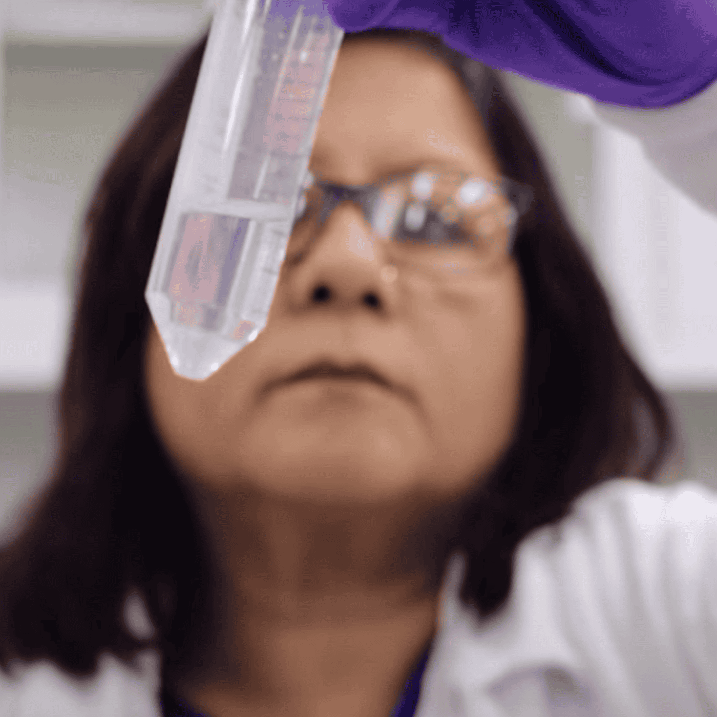 A scientist examines a test tube containing a clear liquid, likely in a laboratory setting