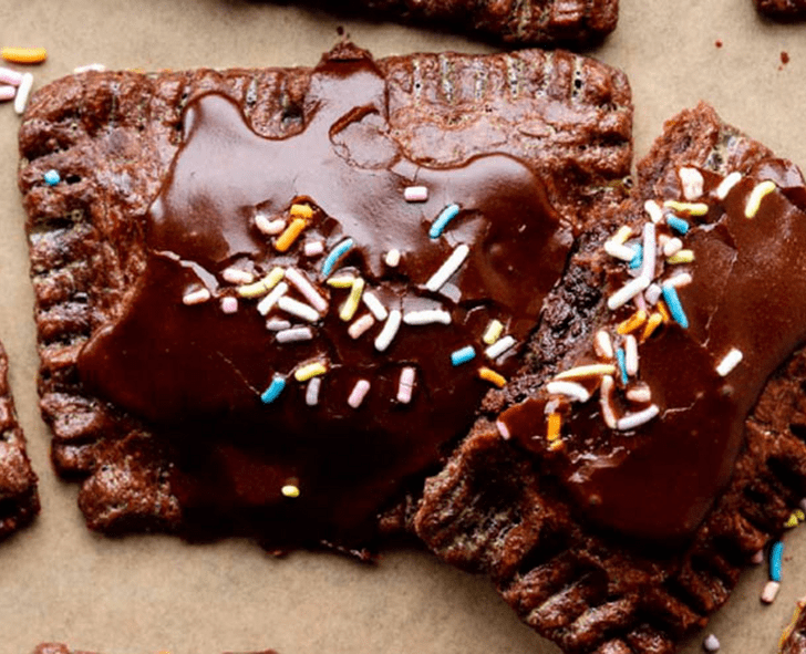 Chocolate pastries with icing and colorful sprinkles, likely a dessert or snack item