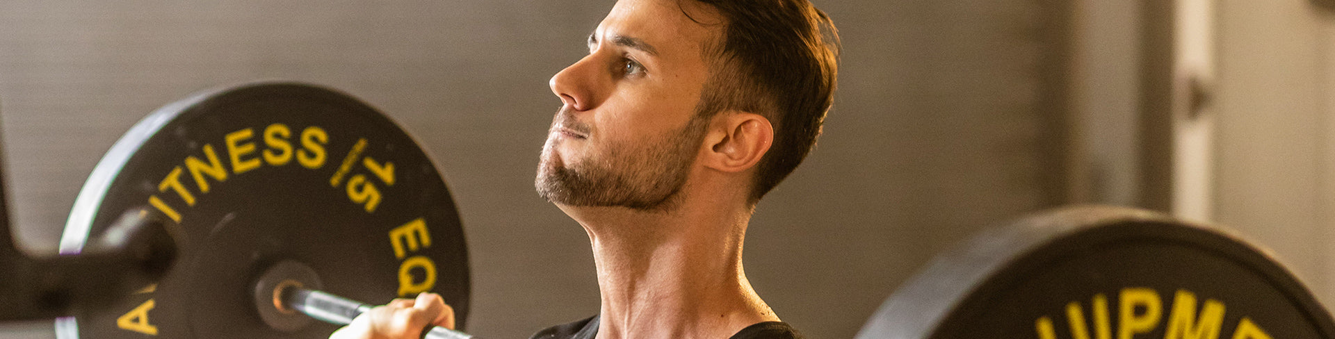 A person lifting a barbell with weight plates in a gym setting