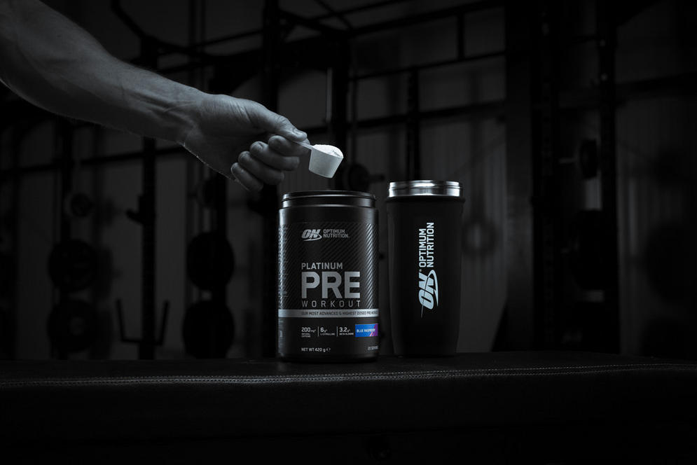 Optimum Nutrition Platinum Pre Workout container with a scoop, next to an Optimum Nutrition shaker bottle