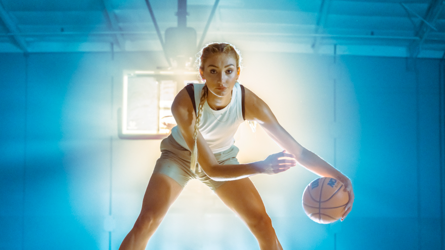 A person playing basketball indoors, holding a basketball in an athletic stance