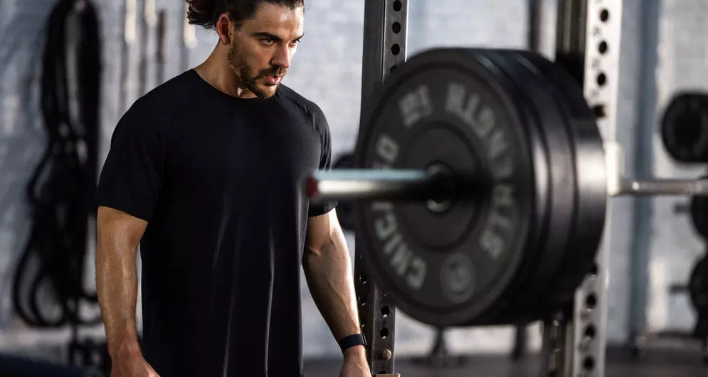 Focused man preparing for a heavy barbell lift in the gym, building strength and muscle mass.
