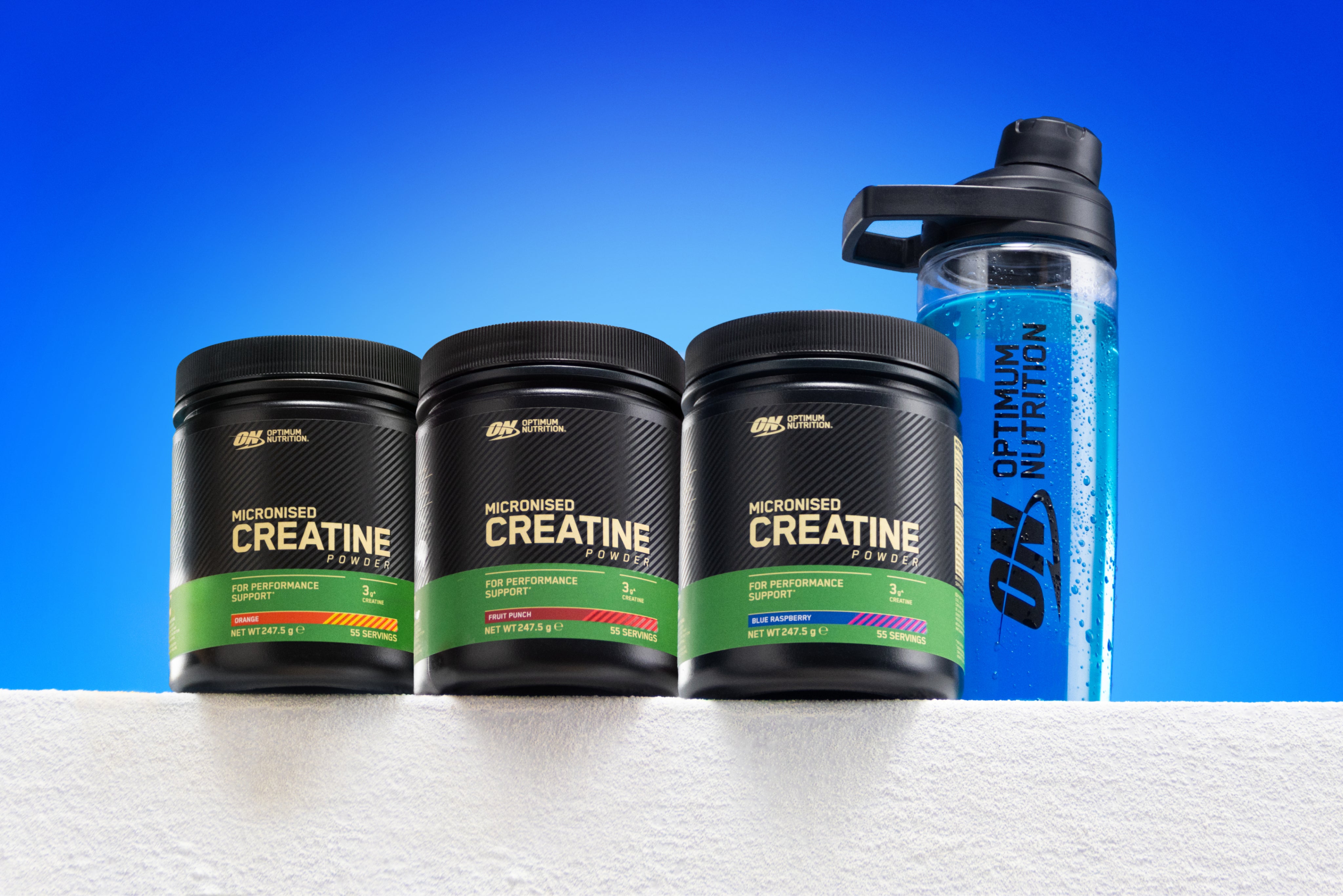 Three Optimum Nutrition Micronised Creatine tubs with a shaker bottle, set against a blue gradient background.