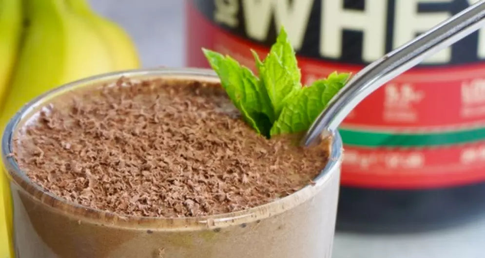 Mint Choc Chip Smoothie standing in front of a Gold Standard Whey Tub