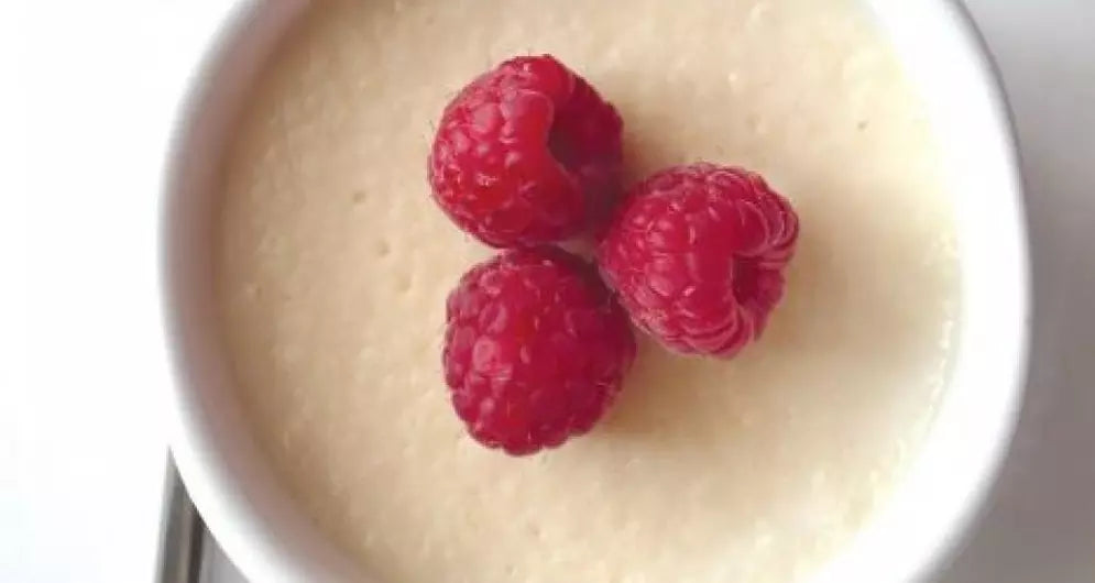 Casein-Pudding in einem weißen Förmchen, garniert mit drei frischen Himbeeren.