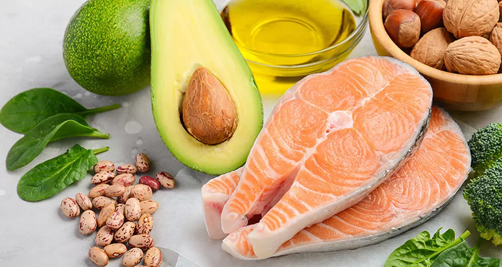Selection of keto-friendly foods including salmon, avocado, olive oil, nuts, and leafy greens.
