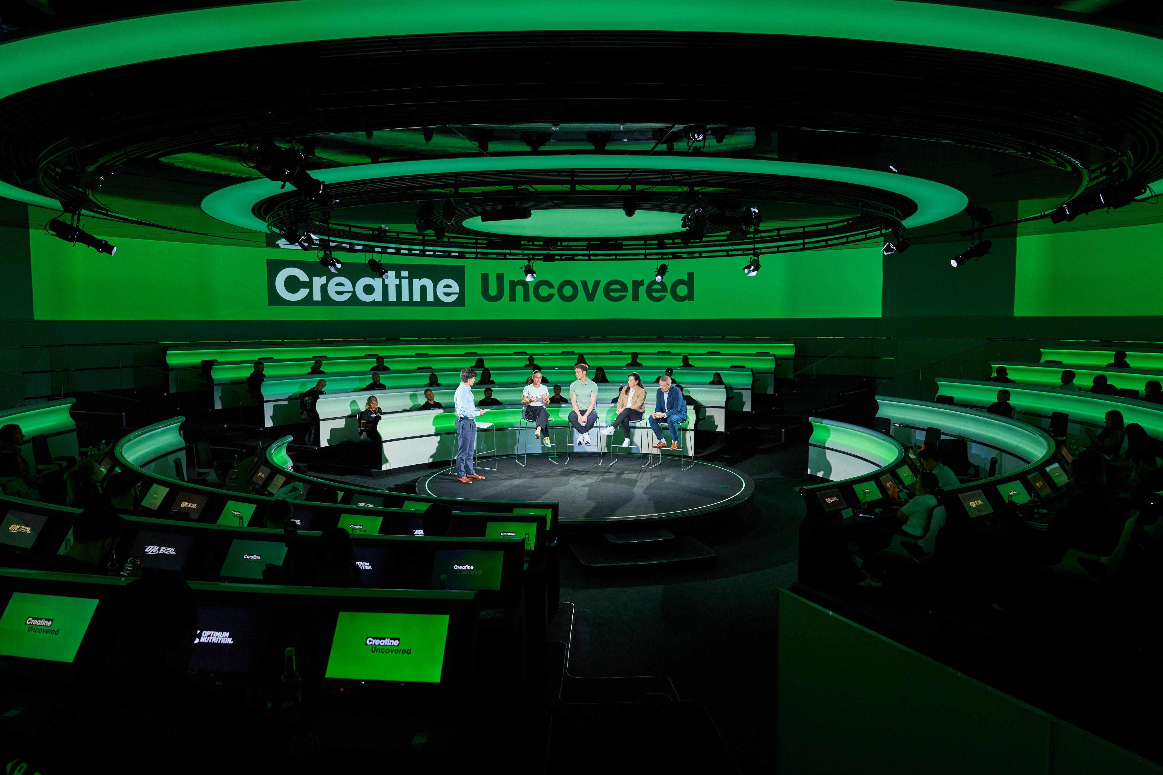 Panel discussion event titled "Creatine Uncovered" with speakers seated in a circular stage setup