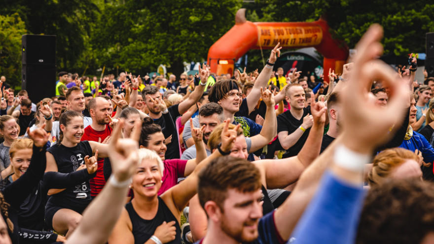 A group of people participating in an outdoor fitness event, raising their hands in enthusiasm