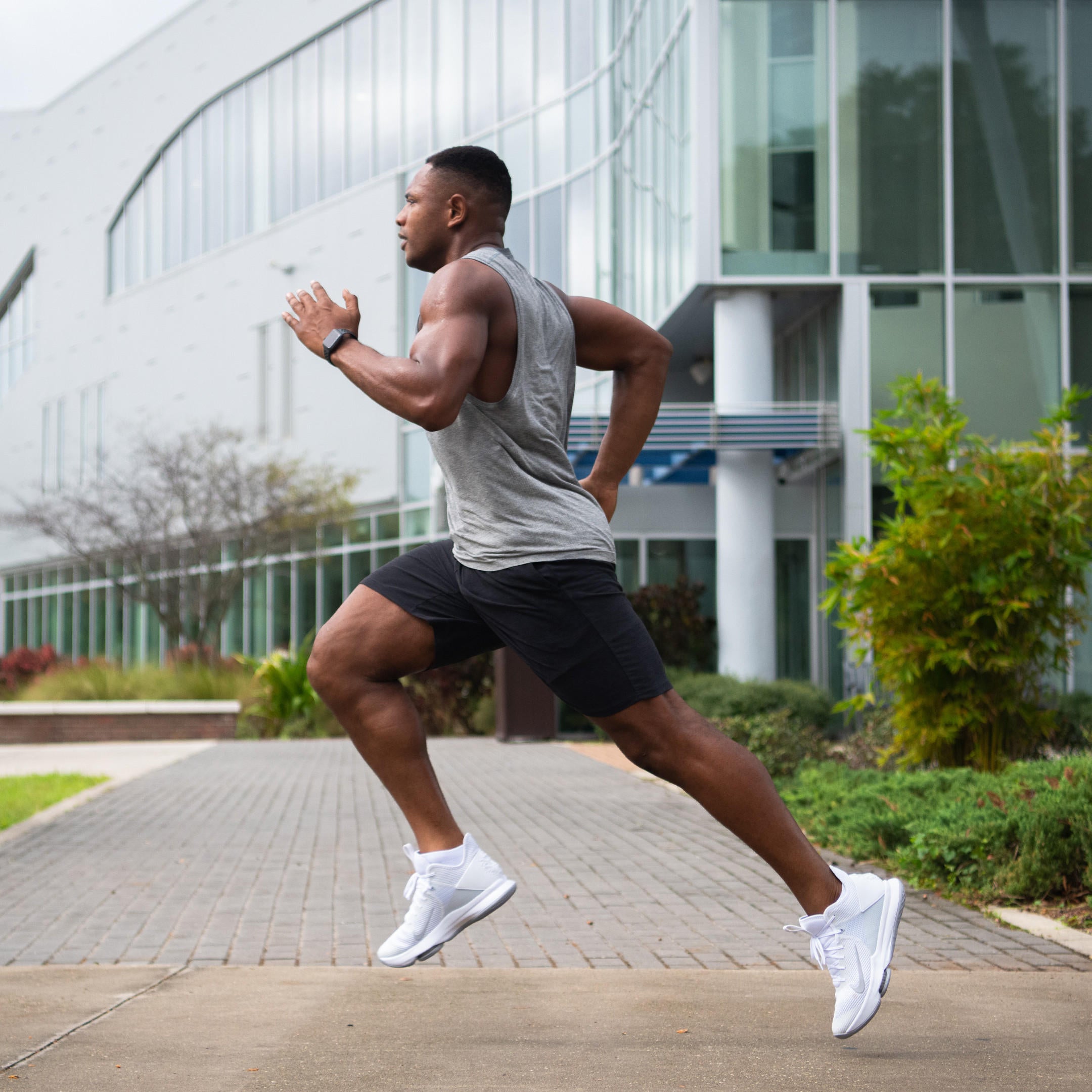 A man running outdoors, wearing athletic clothing and sneakers, demonstrating high-intensity workout activity