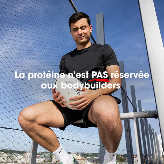 Man holding a container of protein powder while sitting outdoors, with a fence in the background