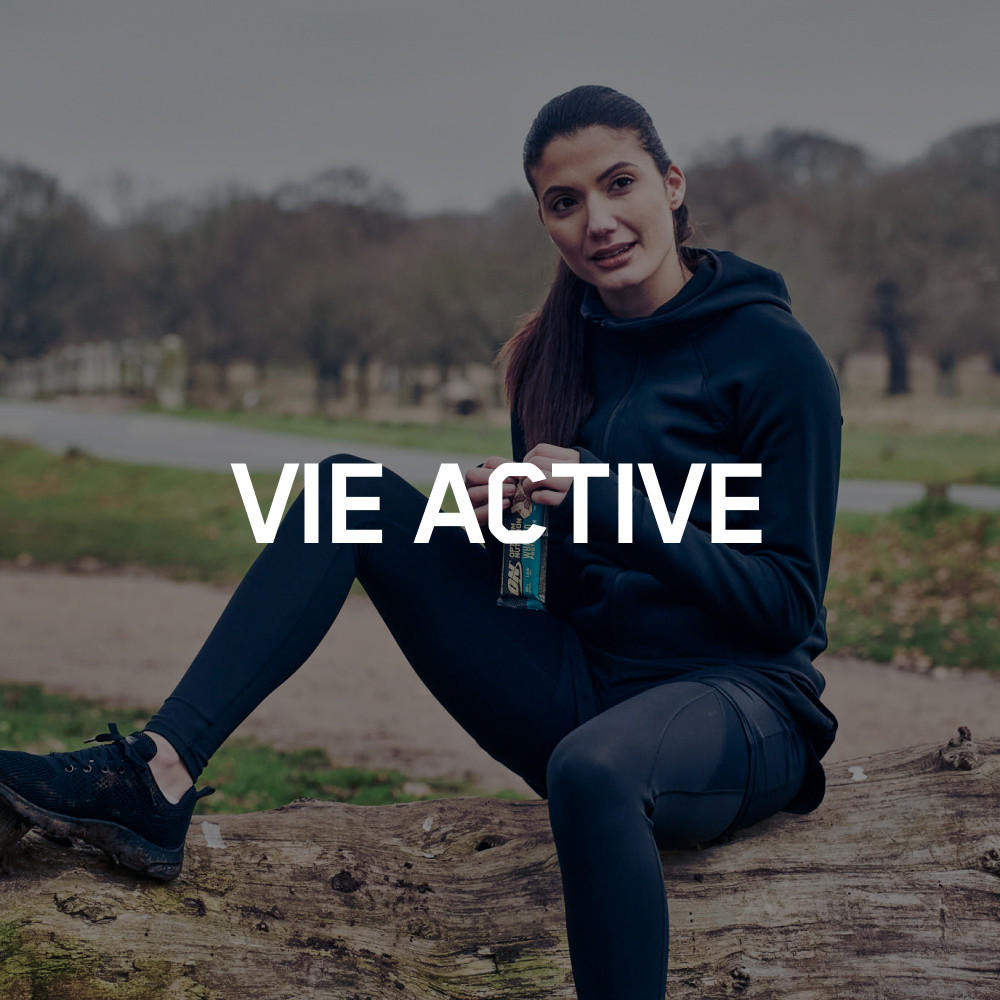 Woman sitting outdoors holding a can of amino energy drink, dressed in activewear