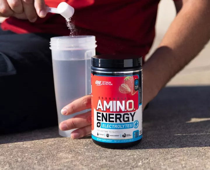 Optimum Nutrition Essential Amino Energy + Electrolytes supplement container with a person adding powder to a shaker bottle