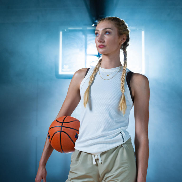 A woman in athletic attire holding a basketball, standing in a gym setting