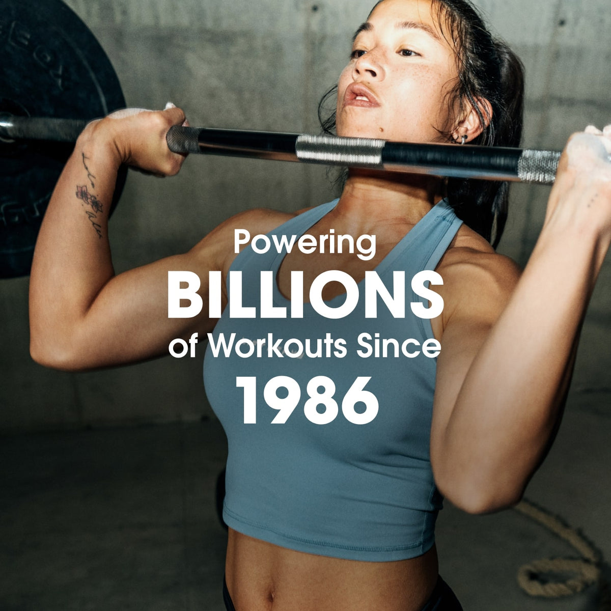 Person lifting a barbell in a gym setting, with text overlay stating Powering Billions of Workouts Since 1986.