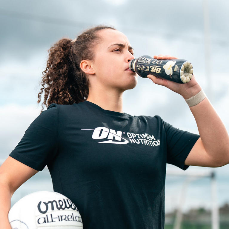Optimum Nutrition athlete drinking ON Essential Amino Energy drink can, holding a sports ball