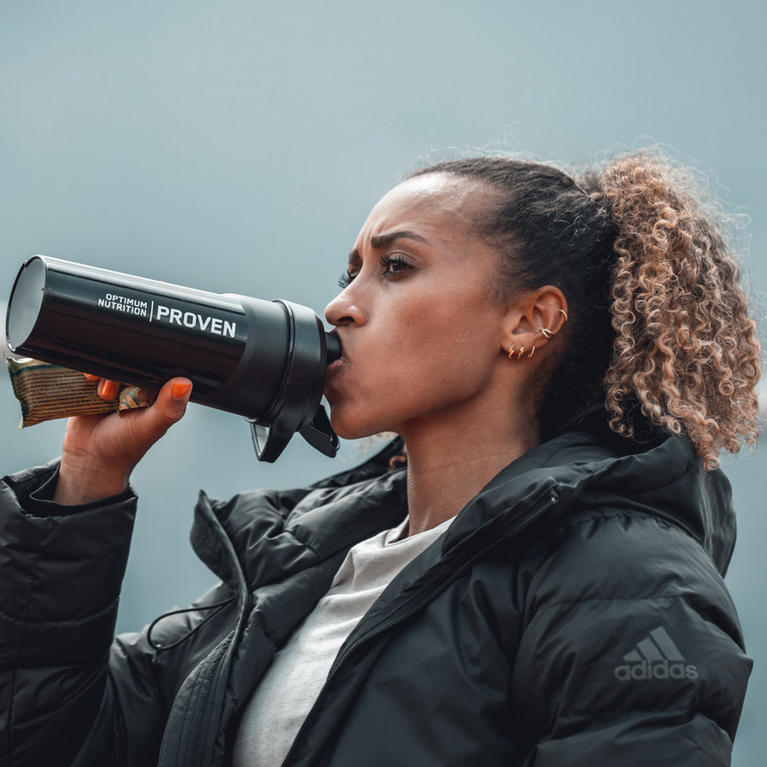 Person drinking from an Optimum Nutrition shaker bottle, suitable for post-workout nutrition and protein shakes