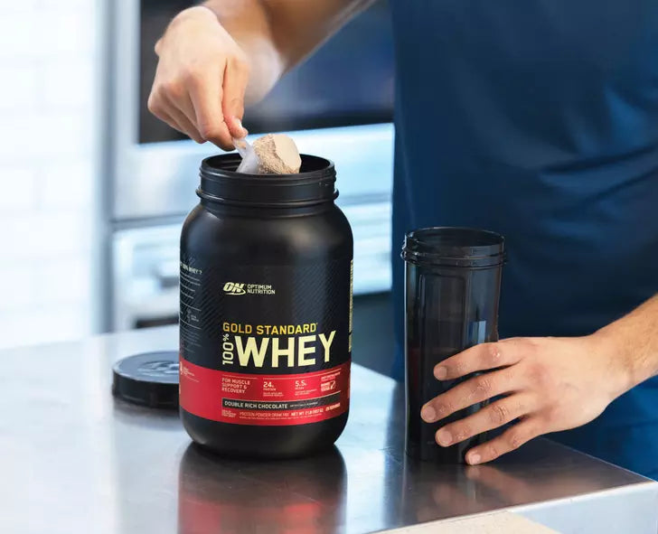 Gold Standard 100% Whey protein powder container with scoop, double rich chocolate flavor