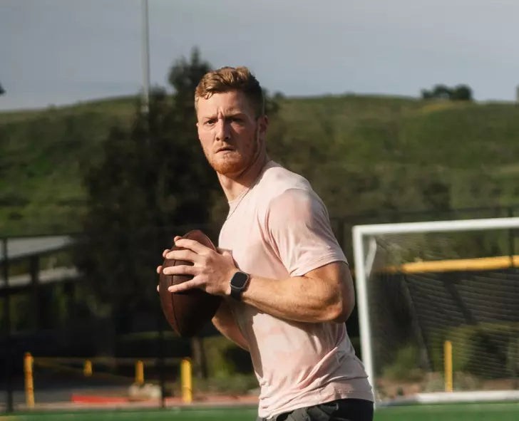 A person holding a football on a field, preparing to throw