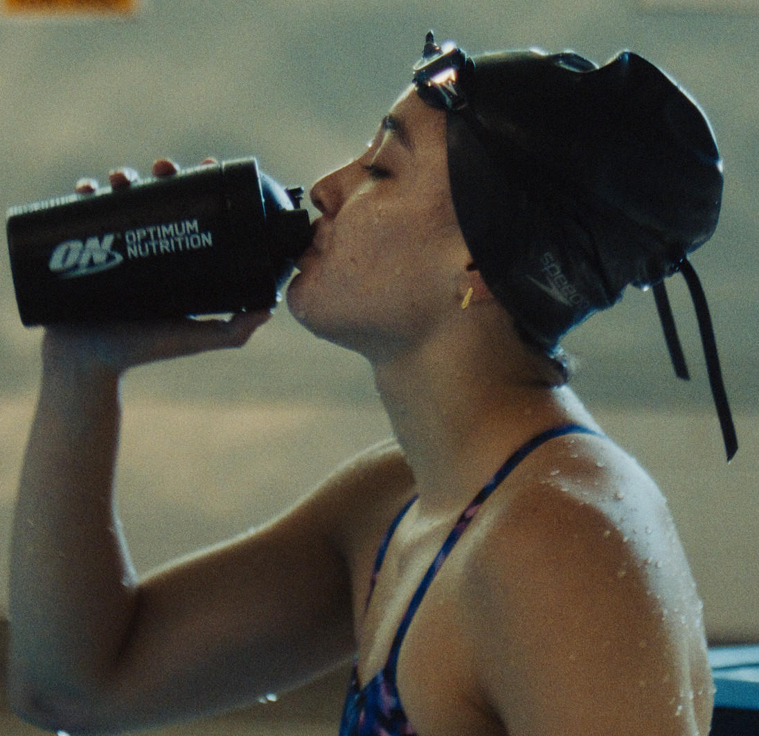 Optimum Nutrition shaker bottle being used by a swimmer, promoting post-workout nutrition
