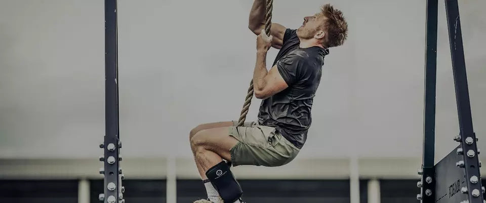 A person climbing a rope during a workout, possibly using amino energy supplements for enhanced performance and endurance