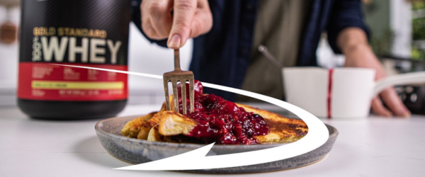 Optimum Nutrition Gold Standard 100% Whey Protein container next to a plate with pancakes and berry topping