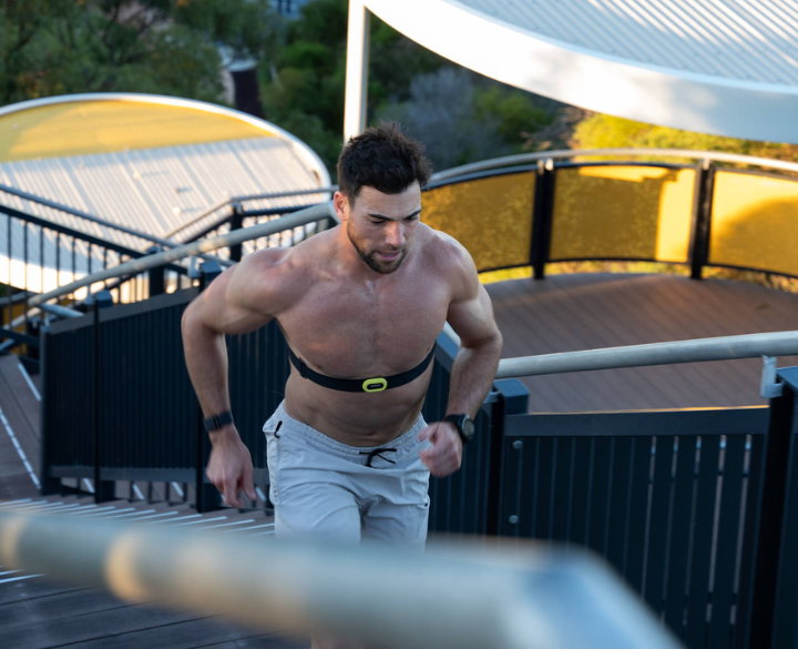 A man running up outdoor stairs wearing a fitness tracker chest strap