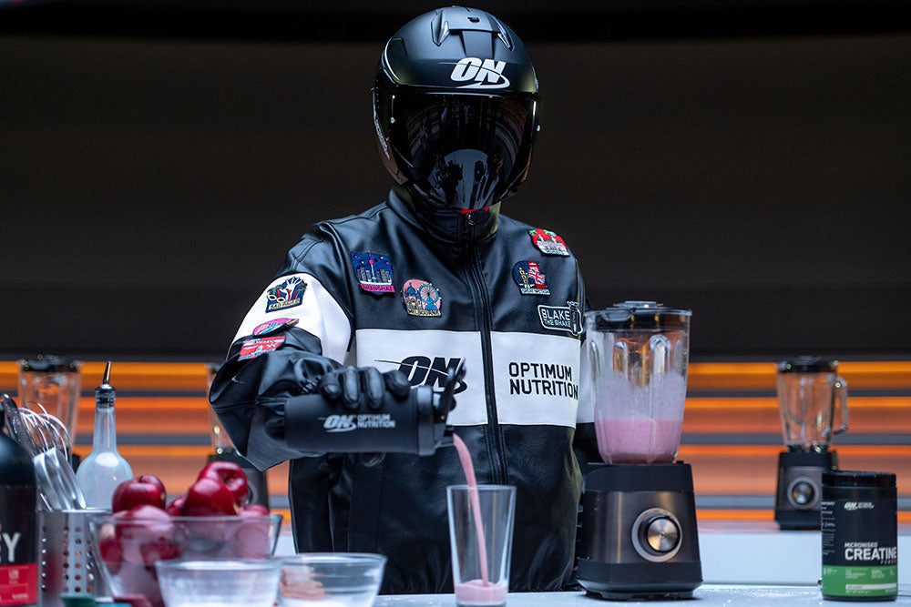 Optimum Nutrition athlete pouring a shake into a glass next to a blender