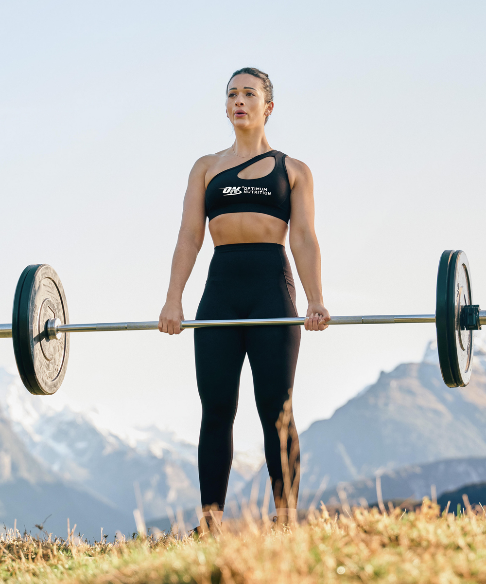 Person lifting a barbell outdoors, wearing athletic clothing with "ON" logo, suggesting fitness or weightlifting activity