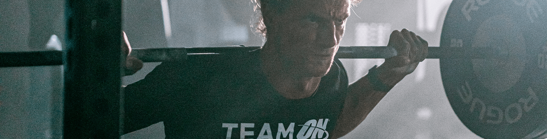 Man lifting a barbell while wearing a "Team ON" shirt, possibly related to Optimum Nutrition products