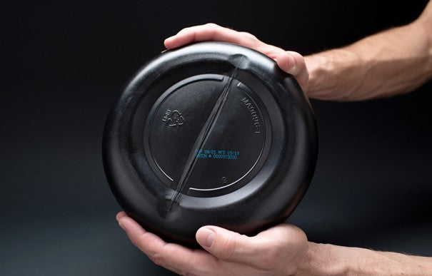 A person holding a black container, possibly for supplements or protein powder