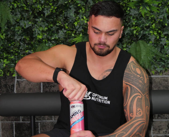 Optimum Nutrition Amino Energy drink can being opened by a person, featuring the brand logo on their tank top