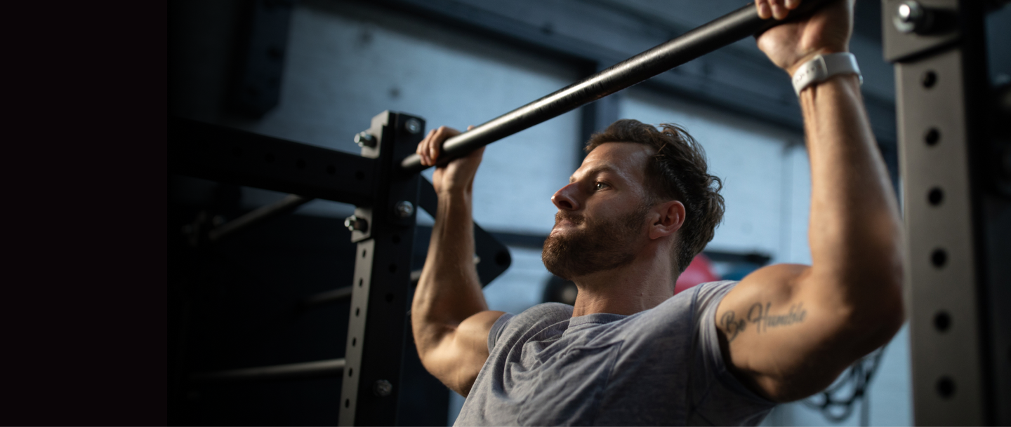A person performing a pull-up exercise on a gym bar, focusing on strength training and muscle building
