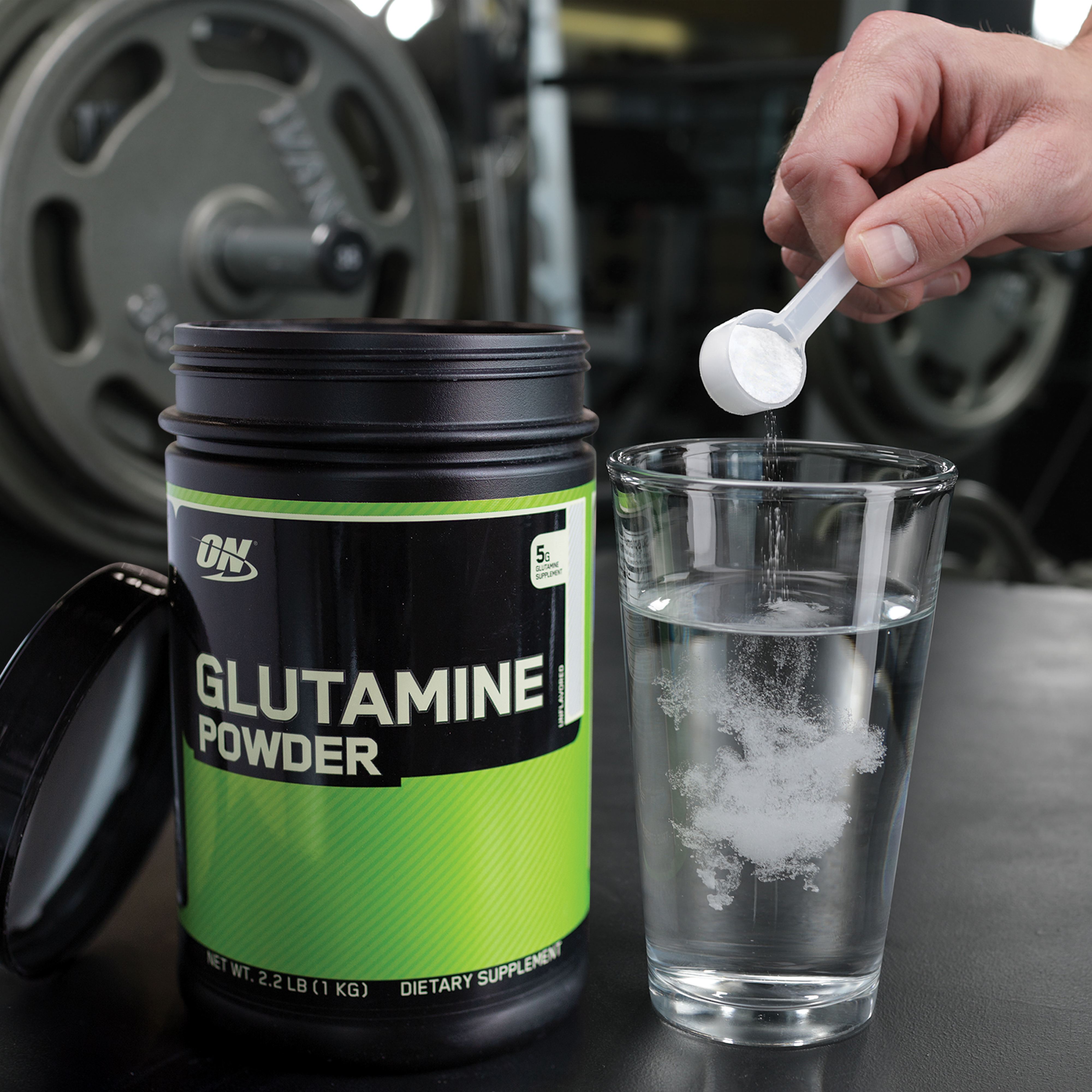 tub of glutamine powder with glass beside it 