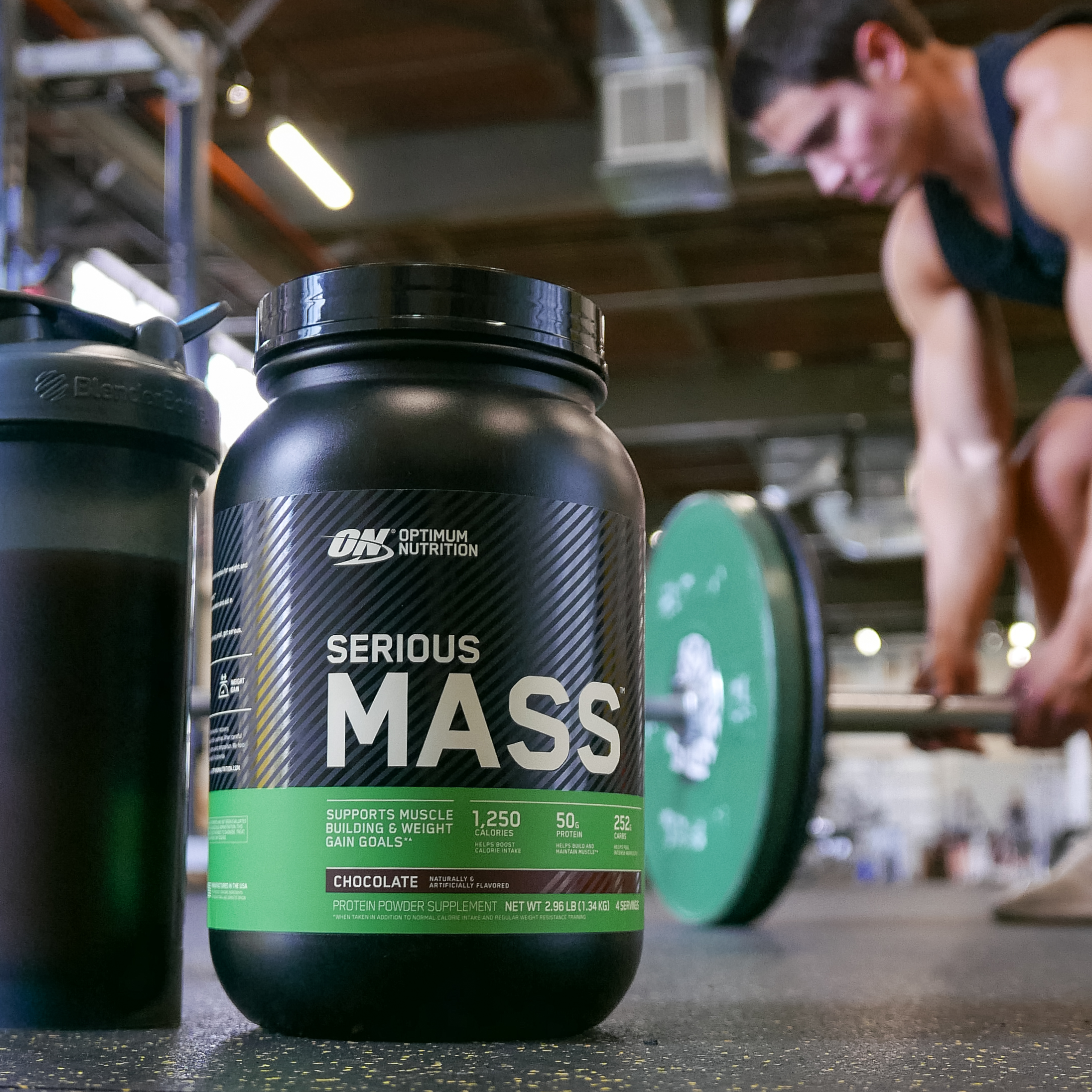 a tub of optimum nutrition serious mass and man in background